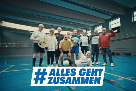 Alles geht zusammen - Gemeinschaft beim Sport Gruppenfoto einer Volleyballmannschaft, die aus älteren Sportlern besteht, in einer Turnhalle. Darüber das Logo der Aktion Alles geht zusammen.
