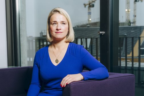 Verena Bentele sitzt auf einem Sofa, hinter ihr sieht man die Silhouette von Berlin.