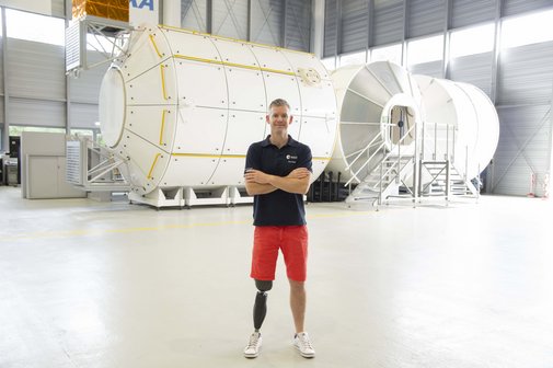 John McFall steht vor einem Trainingsmodul für die Raumfahrt. 