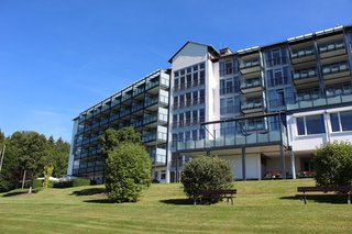 Die helle, moderne Hotel-Fassade mit ihren zahlreichen Balkonen hebt sich deutlich vom strahlendblauen Himmel ab.