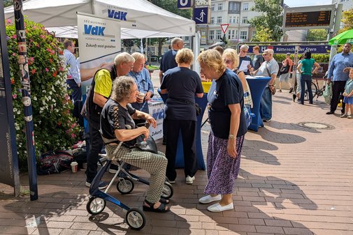 Wilma Kirschmer vom Kreisverband Rhein-Ruhr erklärt einer Besucherin, die auf einem Rollator sitzt, die Leistungen des VdK.
