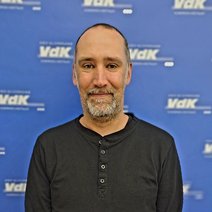 Porträt von Sascha Grieß vor einem Roll-up mit dem Logo des VdK NRW