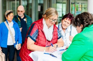 eine Frau trägt sich in eine Liste ein