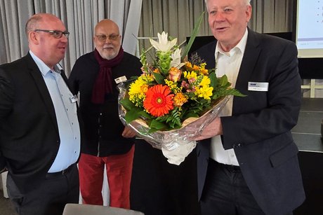 Vorsitzender Peter Jeromin hält einen großen Blumenstrauß , neben ihm Geschäftsführer Marc Thiele. 