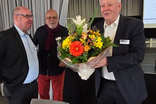 Vorsitzender Peter Jeromin hält einen großen Blumenstrauß , neben ihm Geschäftsführer Marc Thiele. 