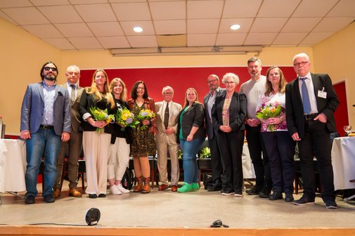 Gro&szlig;es Gruppenfoto mit allen Teilnehmenden der Podiumsdiskussion auf der B&uuml;hne.