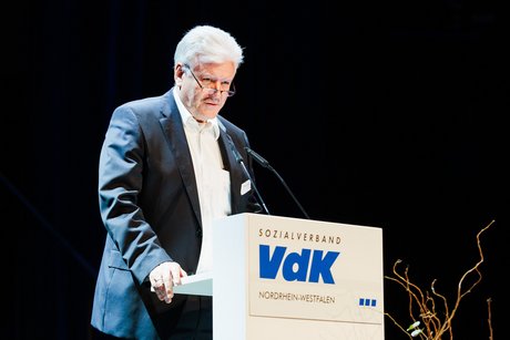 VdK-Vizepräsident Peter Jeromin steht am VdK-Rednerpult und spricht ins Mikrofon.
