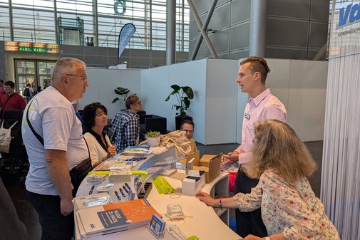 Besucher stehen am Tresen des VdK-Messestands.
