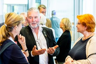 Ein Mann und zwei Frauen stehen im Gespräch zusammen.