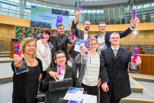 Eine Gruppe vilmA-Preisträgerinnen und -preisträger reckt fröhlich die Pokale in die Höhe.