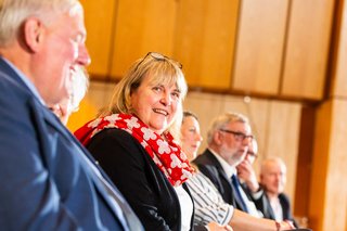 Eine Frau mit geblümten-roten Halstuch lächelt in Richtung Kamera.