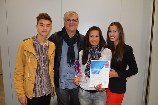 Lächelnde Preisträgerin mit Urkunde und Pokal in der Hand, rechts und links drei Menschen als Begleitung. l.,