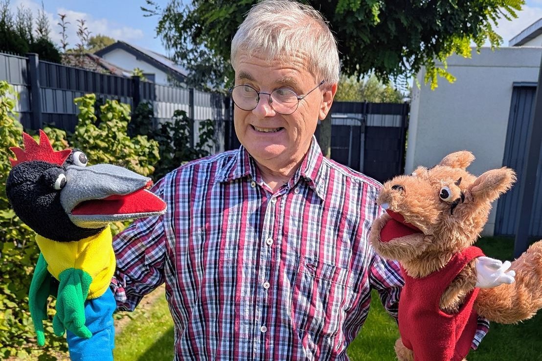 Bernard Bauguitte hält im Garten zwei seiner Puppen in den Händen.