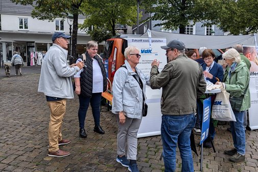 Menschen stehen auf dem Olper Marktplatz vor dem Stand des Sozialverbands VdK NRW.