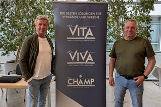 Zwei Männer stehen rechts und links neben einem Roll-Up des Unternehmens Vita.