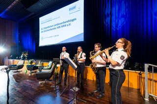 Zwei Männer und eine Frau mit Saxofon und eine Frau mit Klarinette spielen gemeinsam am Rand der großen Bühne der Stadthalle Neuss.