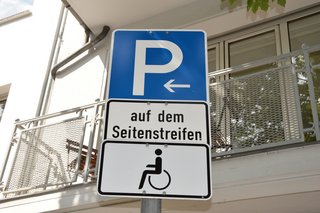 Parkkplatzschild mit Rollstuhlsymbol zur Kennzeichnung eines Behindertenparkplatzes.