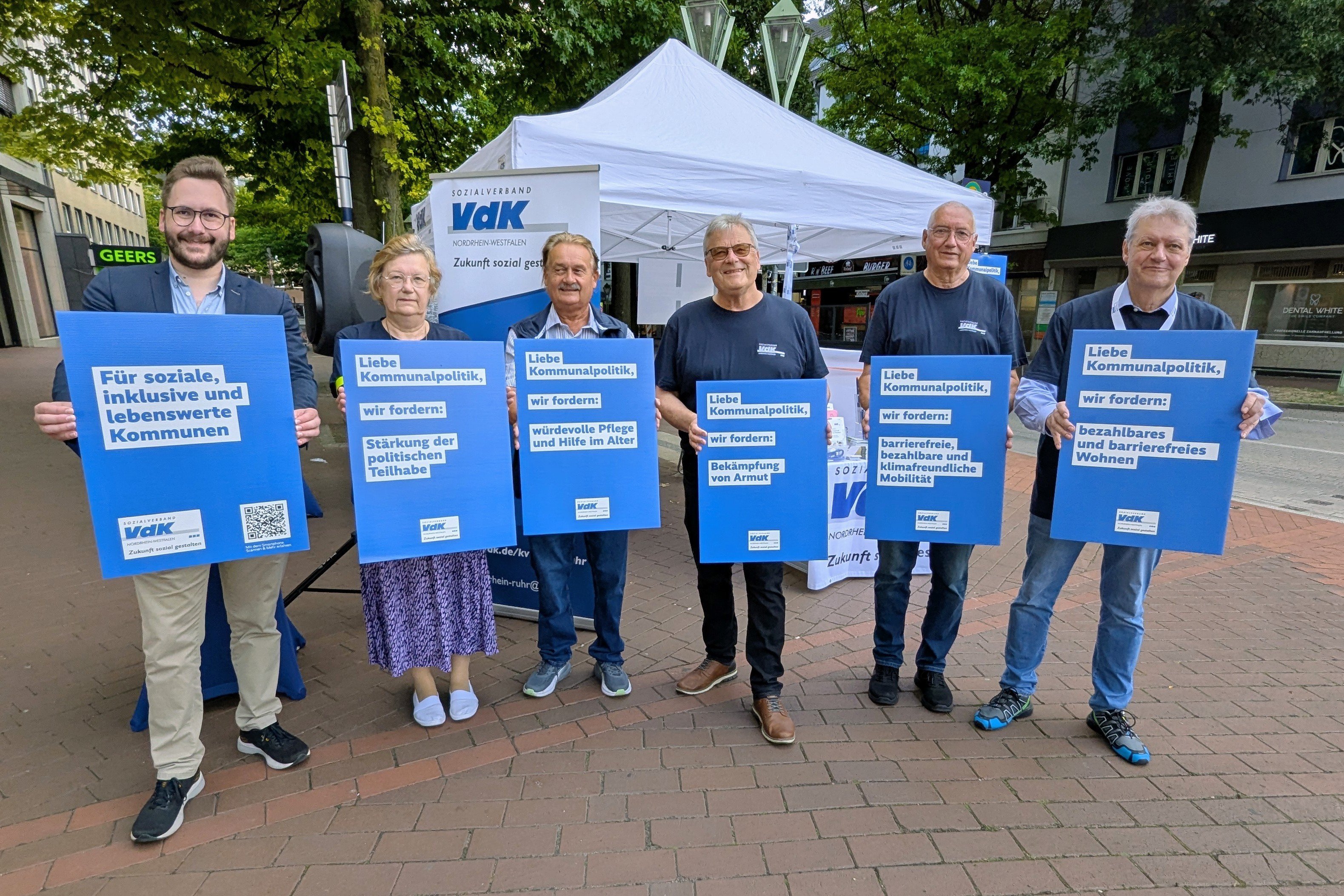 1 Frau und 5 Männer halten mit beiden Händen blaue Plakate in die Kamera. Auf den Plakaten stehen verschiedene sozialpolitische Forderungen des VdK drauf.