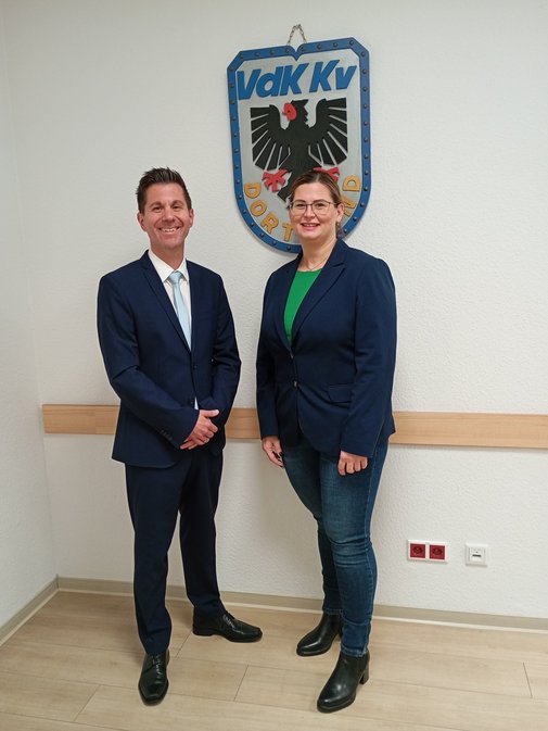 Ein Mann und eine Frau stehen nebeneinander vor dem Wappen des Kreisverbands Dortmund