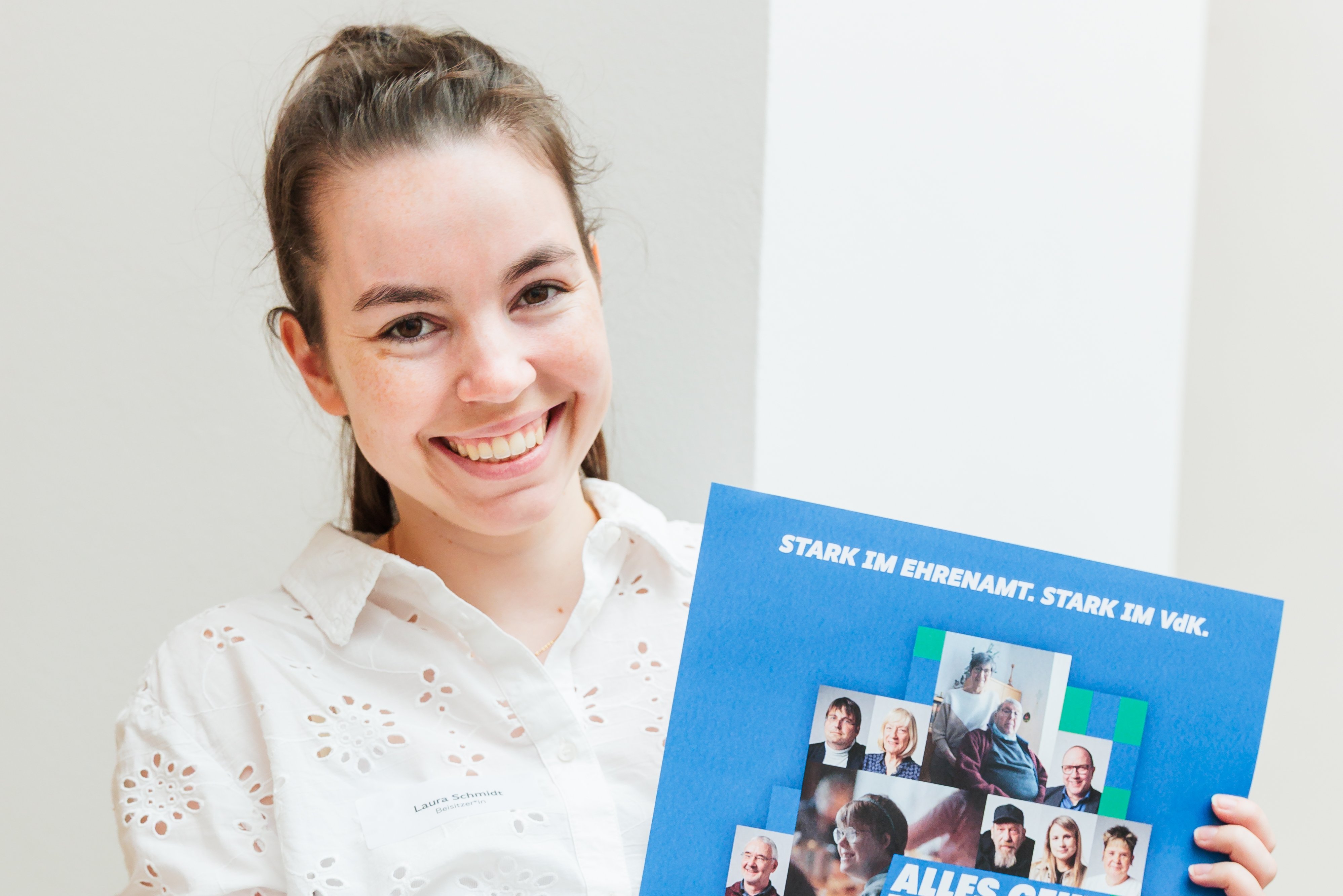 Laura Schmidt hält lächelnd ein Plakat der Ehrenamtsaktion in den Händen