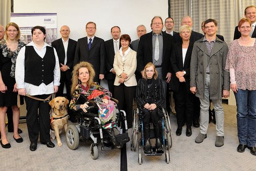 Eine große Gruppe Menschen, stehend und im Rollstuhl sitzend. 