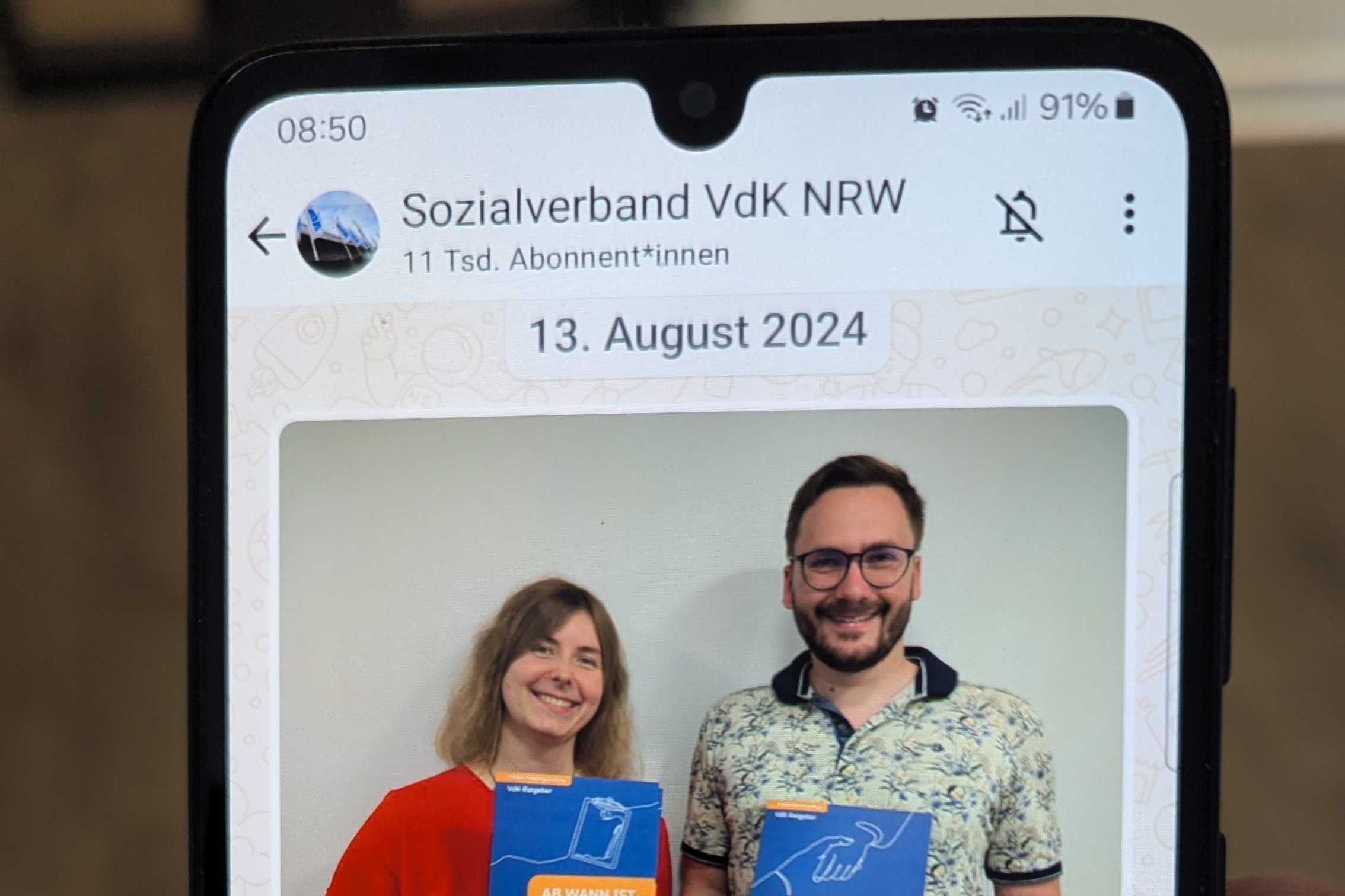 Abfotografierter Smartphone-Bildschirm mit einer aktuellen Meldung zu den neuen Pflegebroschüren im WhatsApp-Kanal.
