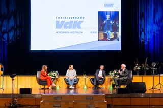 Vier Menschen sitzen auf der Bühne auf Sesseln und diskutieren über die Zukunft des Sozialstaats.