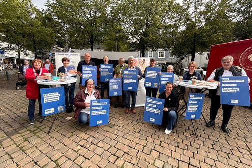 Eine Gruppe von Menschen hält Schilder mit Forderungen des Sozialverbands VdK NRW hoch.