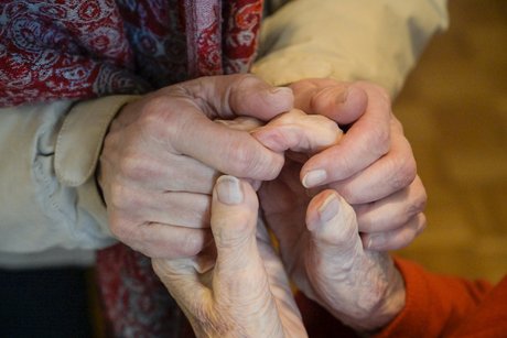 Die Hände einer alten Frau werden festgehalten