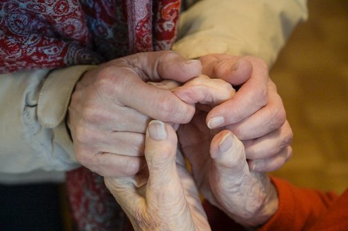 Die Hände einer alten Frau werden festgehalten