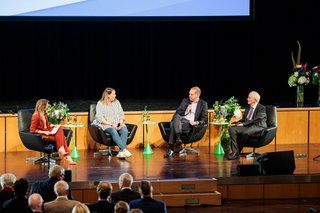 Vier Menschen sitzen gemeinsam auf der Bühne und diskutieren über die Zukunft des Sozialstaats. 