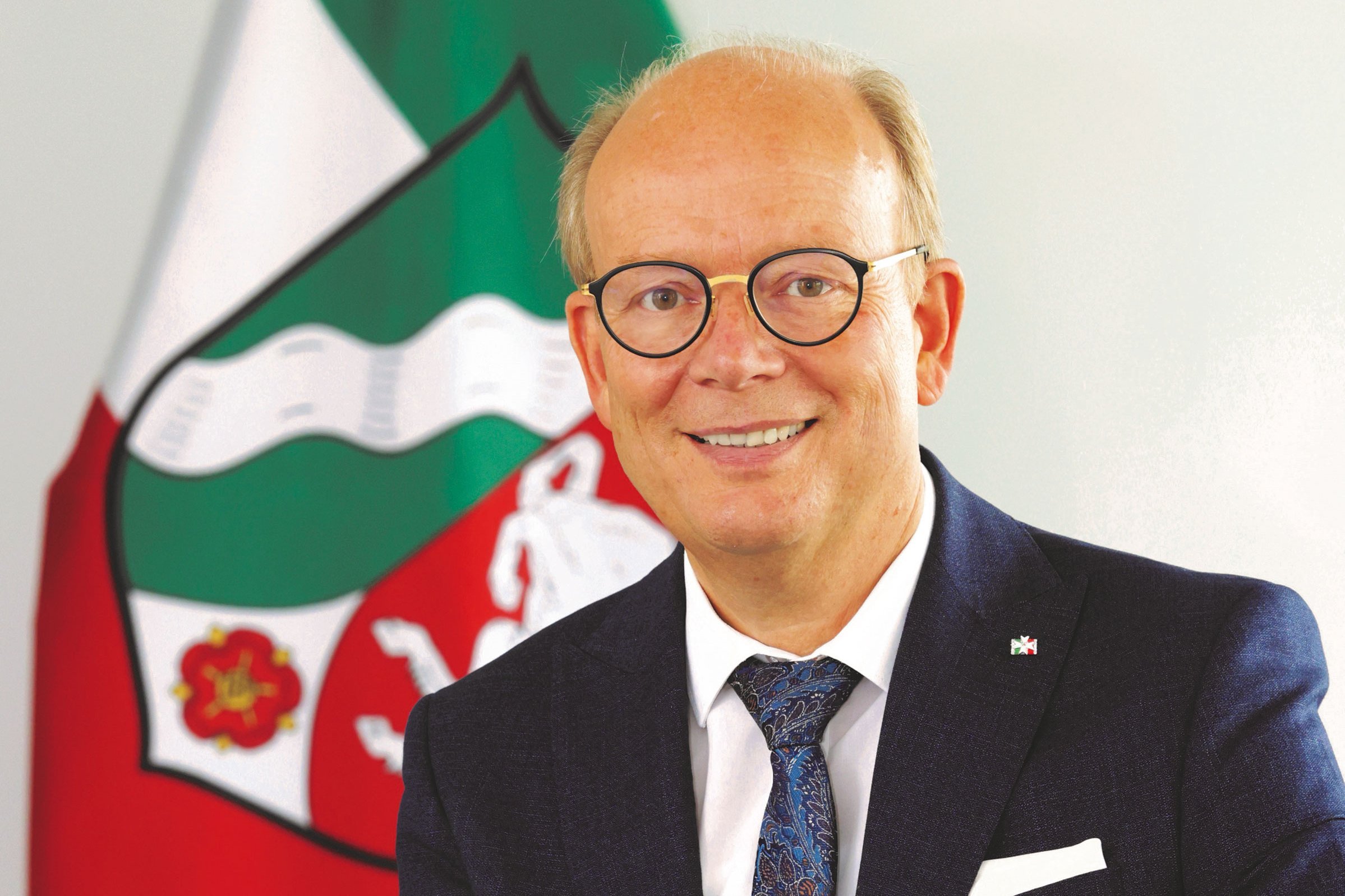 Porträt von André Kuper vor der NRW-Flagge.