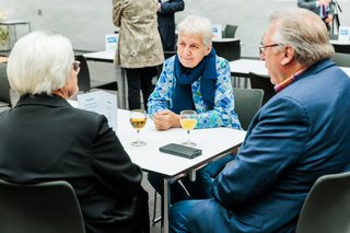 Gäste sitzen im Gespräch an einem Tisch.