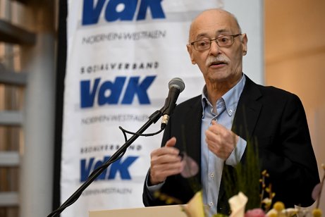 Horst Vöge an einem Rednerpult mit Mikrofon. Im Hintergrund ein Banner mit VdK-Logos.