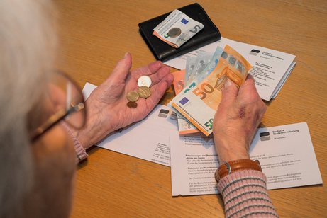 Alte Frau mit Rentenbescheid hält Bargeld in den Händen