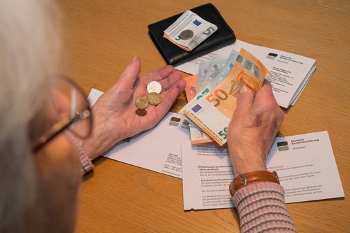 Alte Frau mit Rentenbescheid hält Bargeld in den Händen