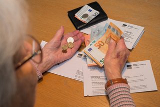Alte Frau mit Rentenbescheid h&auml;lt Bargeld in den H&auml;nden