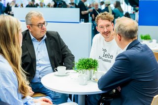 Vier Menschen im Gespräch an einem Tisch des VdK-Stands.