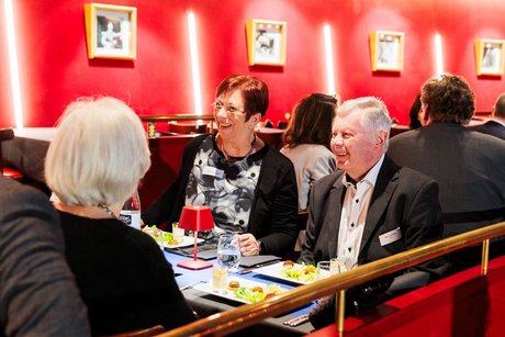 Zwei Frauen und ein älterer Mann sitzen gemeinsam an einem Tisch. Vor ihnen stehen Teller mit einer Salat-Vorspeise.