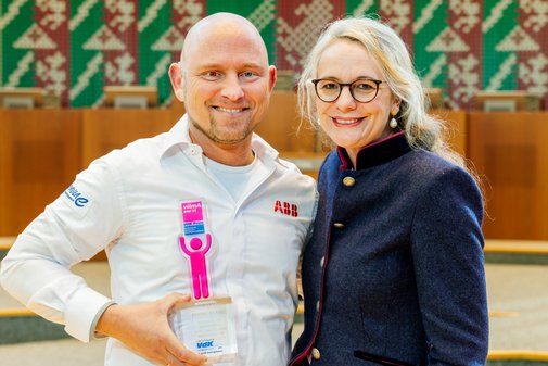 Ein Mann mit Glatze und kurzem, blonden Kinnbart und wei&szlig;em Hemd h&auml;lt l&auml;chelnd den vilmA-Preis in der Hand. Neben ihm eine Frau mit Brille und blonden langen Haaren und dunkler Bluse.