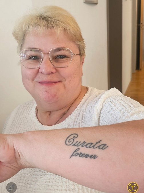 Portrait von Marion Mellinghoff, die ihren tätowierten Arm zeigt: Curata forever.