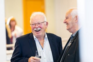 Zwei Männer stehen im Foyer der Stadthalle, einer von ihnen lacht in die Kamera.