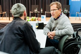 VdK-Mitarbeiter Martin Franke an einem Tisch im Gespräch mit SoVD-Sprecher Dr. Michael Spörke.