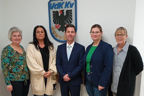 Vier Frauen und ein Mann stehen unter dem Wappen des VdK Kreisverbands Dortmund