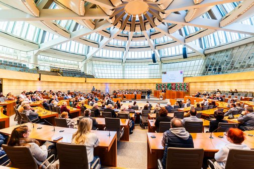 Blick in den vollbesetzten Plenarsaal des Landtags mit gläserner Kuppel. 