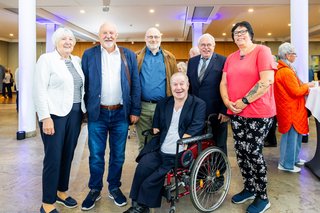 Gruppenfoto. Drei Männer und zwei Frauen stehen nebeneinander. Vor ihnen in der Mitte sitzt ein Mann im Rollstuhl.