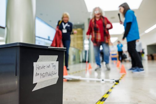 Eine Frau mit Brille und Blindenstock l&auml;uft einen Barriere-Parcours entlang