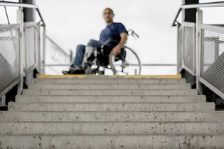Ein Rollstuhlfahrer steht oberhalb einer langen Treppe
