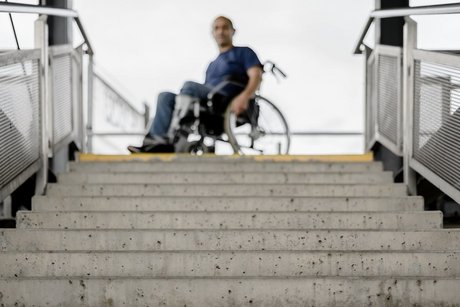 Ein Rollstuhlfahrer steht oberhalb einer langen Treppe