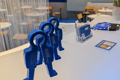Blaue Aufdrehhilfen mit VdK-Logo in Männchenform stehen auf dem Tresen des VdK-Messestands.